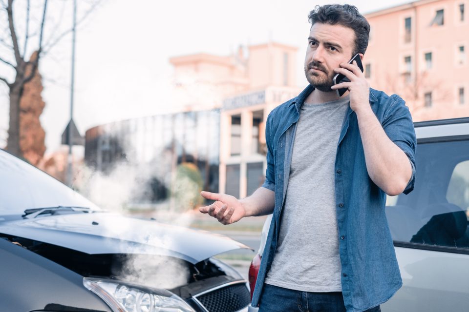 Man calling roadside emergency after car accident